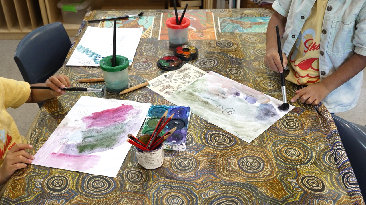 Children painting with watercolours at a shared table