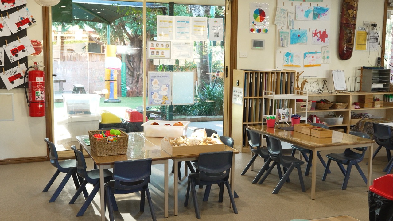 Activity tables set up beside windows looking out to the outdoor play area