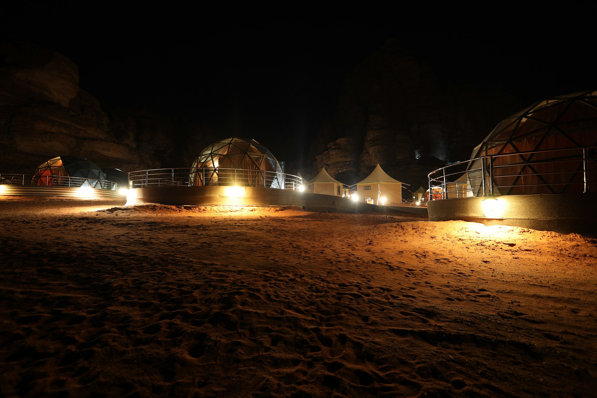 Illuminated desert camp tents at dusk
