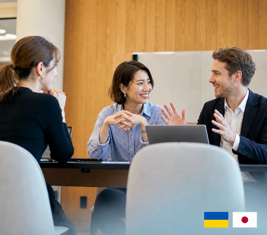 Business professionals discussing ideas around a laptop during a Ukraine-Japan collaboration meeting