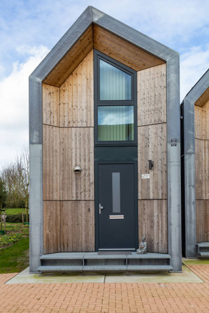 Moderne houten tiny house met een zwarte voordeur en grote ramen onder een paarsblauwe hemel.