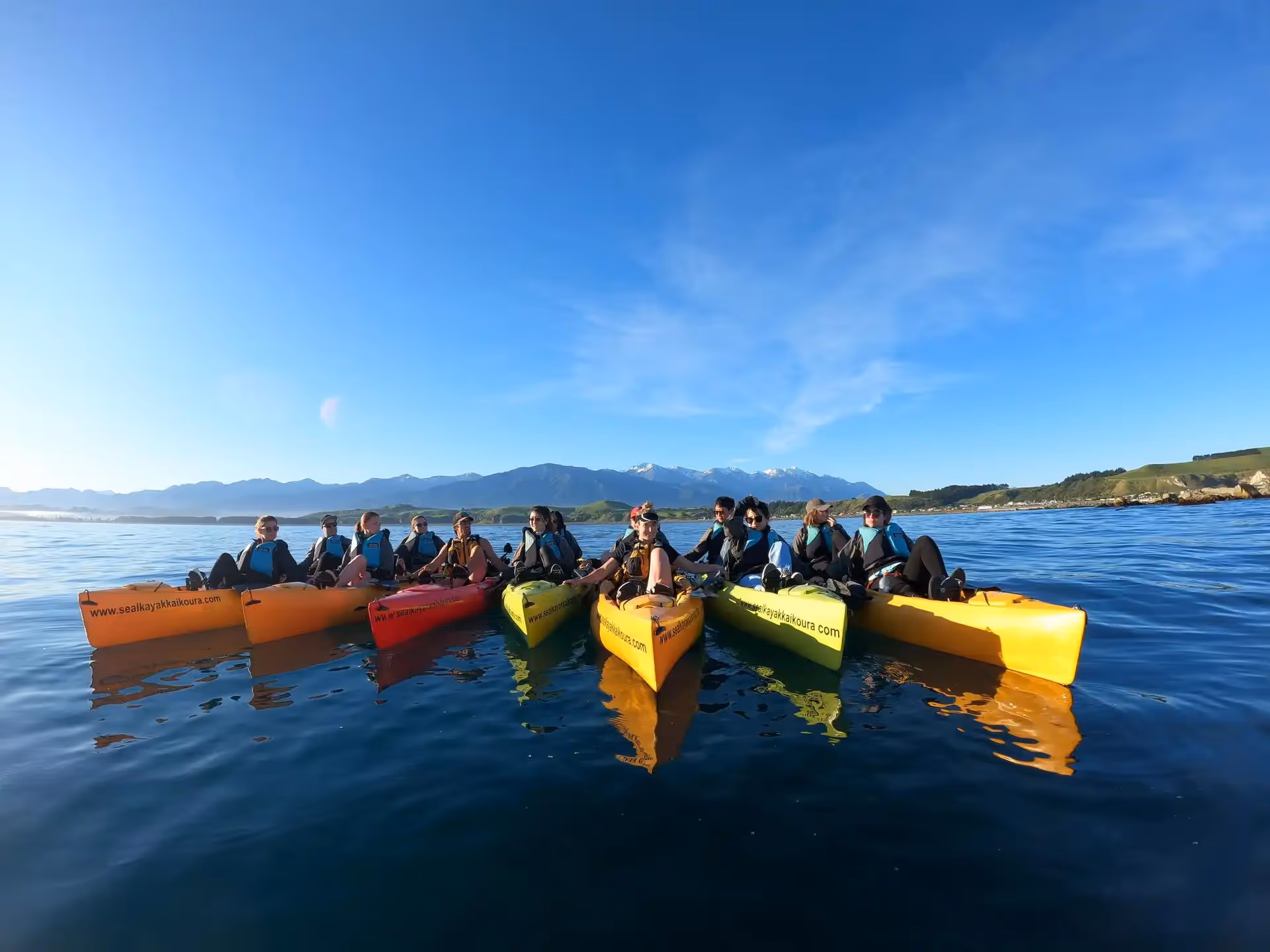 7 kayaks on the water with paddlers on each
