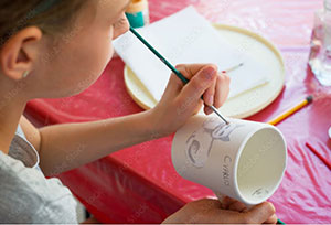 person painting a ceramic mug