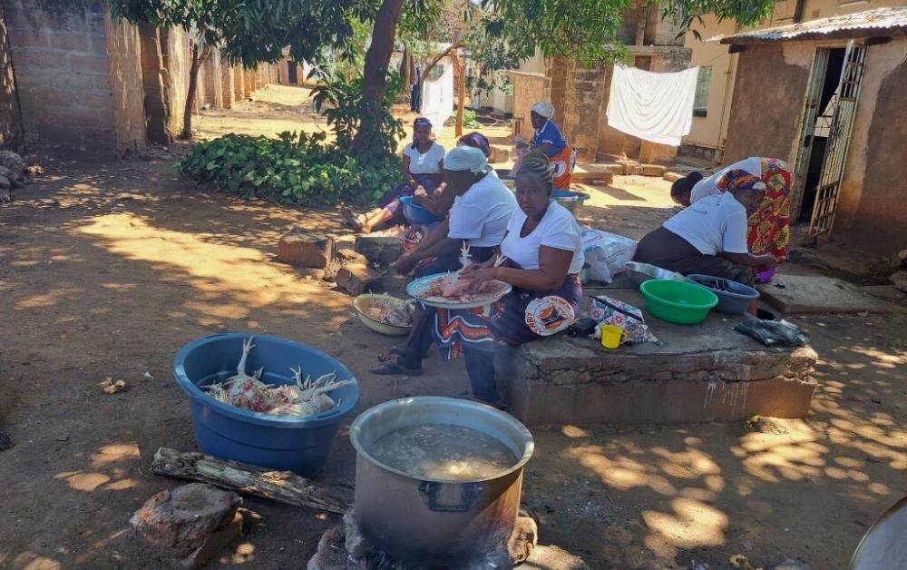 Kochen unter freiem Himmel im Hinterhof der Maria Regina Schule in Sambia – Mitarbeitende bereiten Mahlzeiten für Schulkinder zu