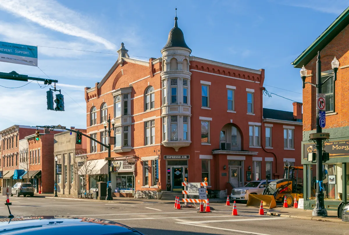 Street view of historic red brick buildings with turret and road closed signs in a small town.
