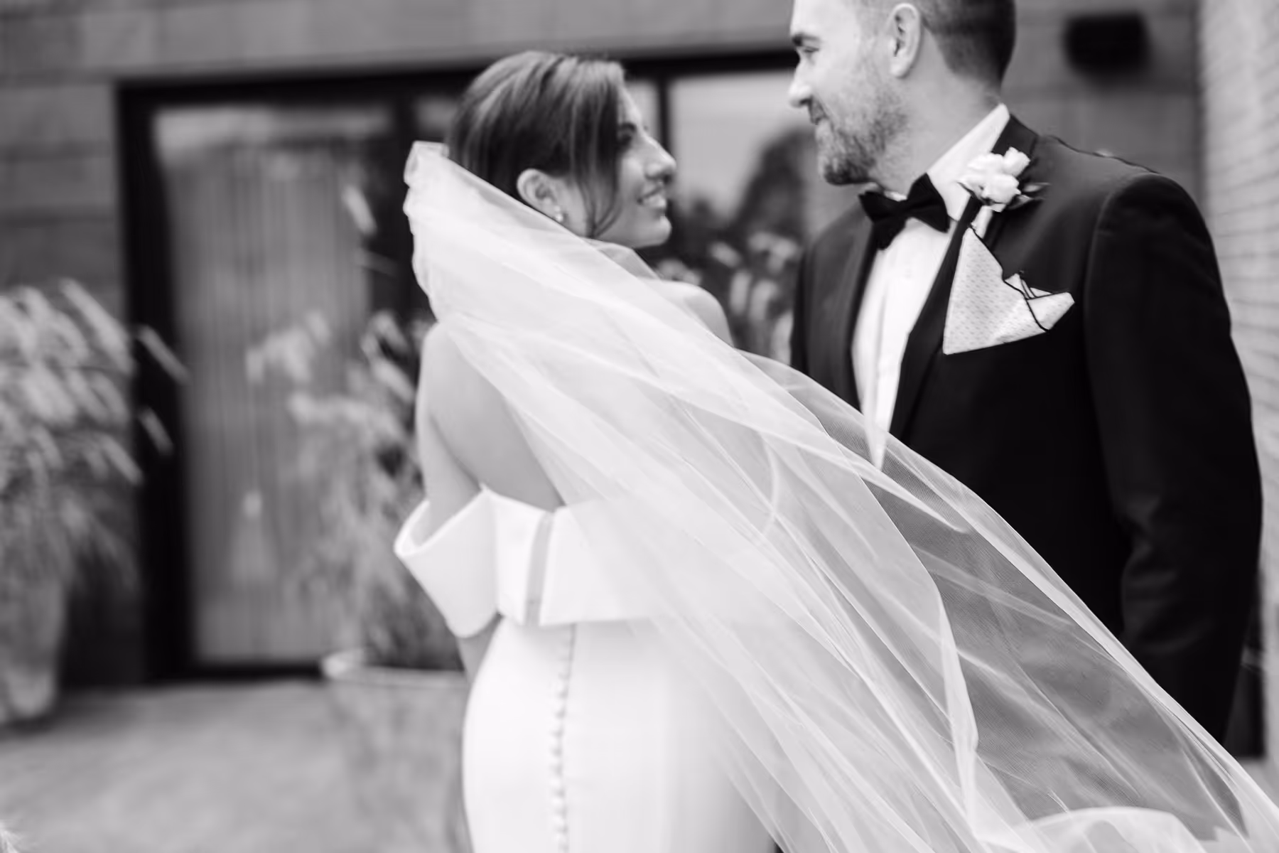 Bride and groom together with veil flowing in the wind.