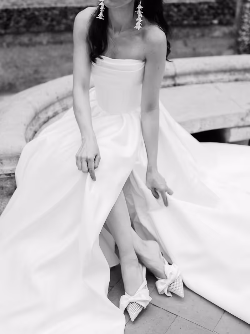 Bride sitting down holding her dress up a but to show off her shoes.