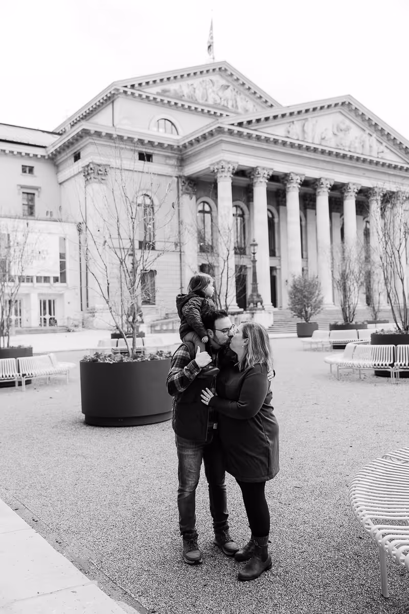 Little girl on her dad shoulders while he kissed mom in front of the Staatsoper.