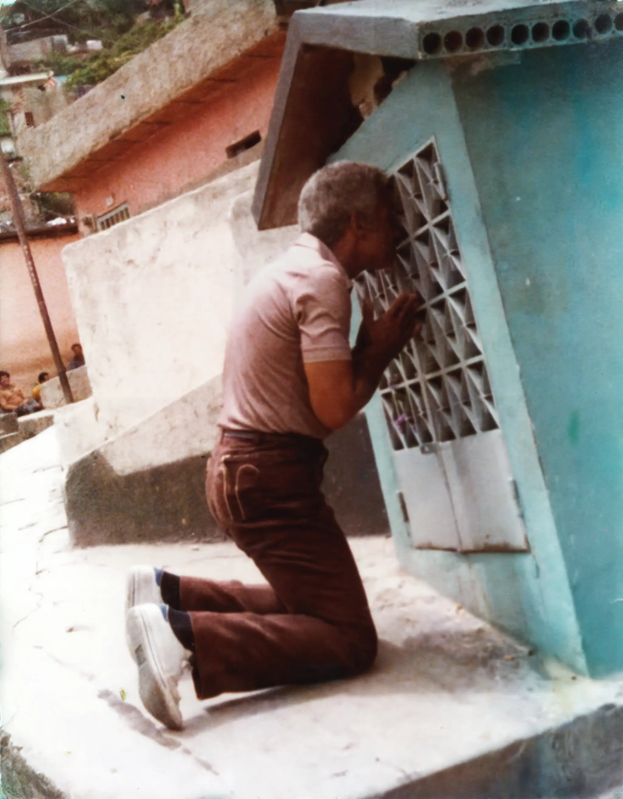 Ismael arrodillado frente a una casa en Portobelo, Panamá. Circa 1980s. Fuente: Archivo de la Fundación Ismael Rivera.