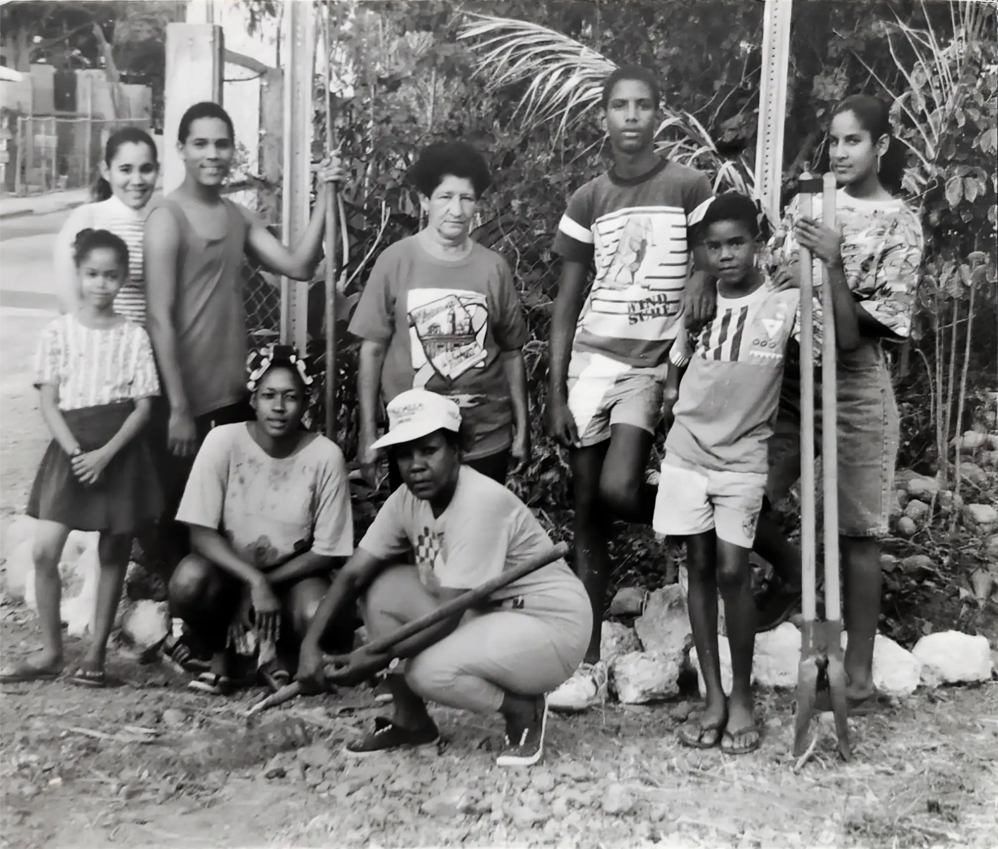 Mejoras al letrero Bienvenidos a La Cuarta por niñas, niños y jóvenes de la comunidad liderado por Aleja Alvarado Sánchez (al frente en cuclillas). Circa 1990.