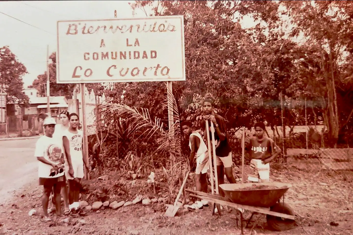 Foto de la colocación del icónico y recordado letrero que estuvo por muchos años justo a la  entrada del Barrio La Cuarta. En ella se observa a la líder comunitaria Alejandrina Alvarado Sánchez junto a jóvenes de la comunidad. Circa 1990. 