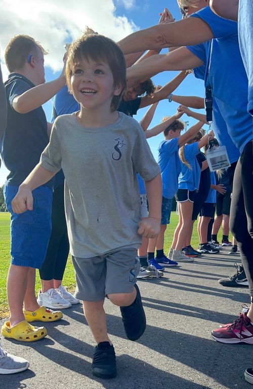 A young TVM student running underneath other student's arms.