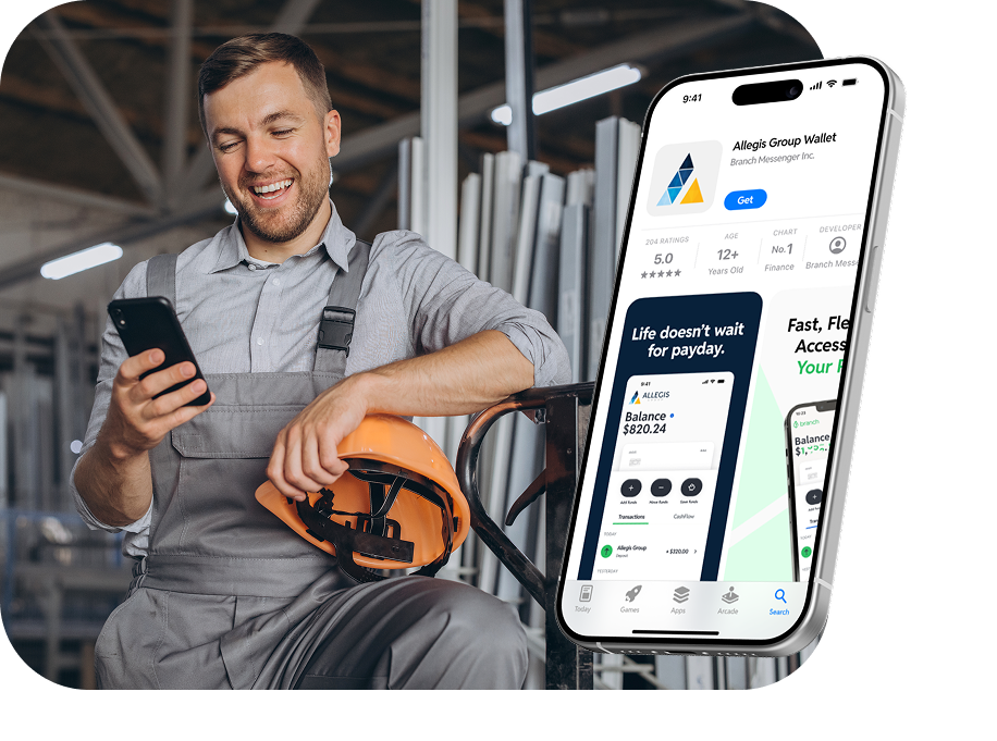 Smiling worker in grey overalls holding an orange helmet and smartphone with a mobile wallet app screen.