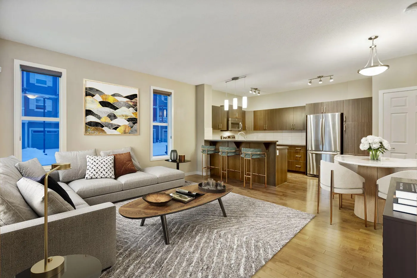 Virtually staged living room with a grey sofa, patterned rug, wood coffee table and wall art, with the kitchen and dining area behind