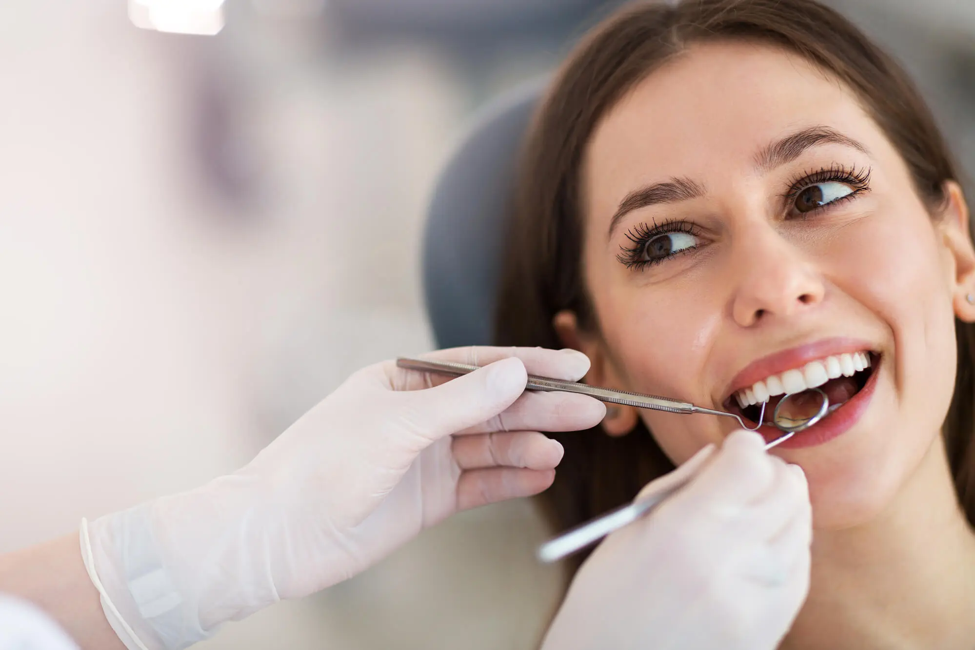 A smiling woman having her teeth examined by a dentist