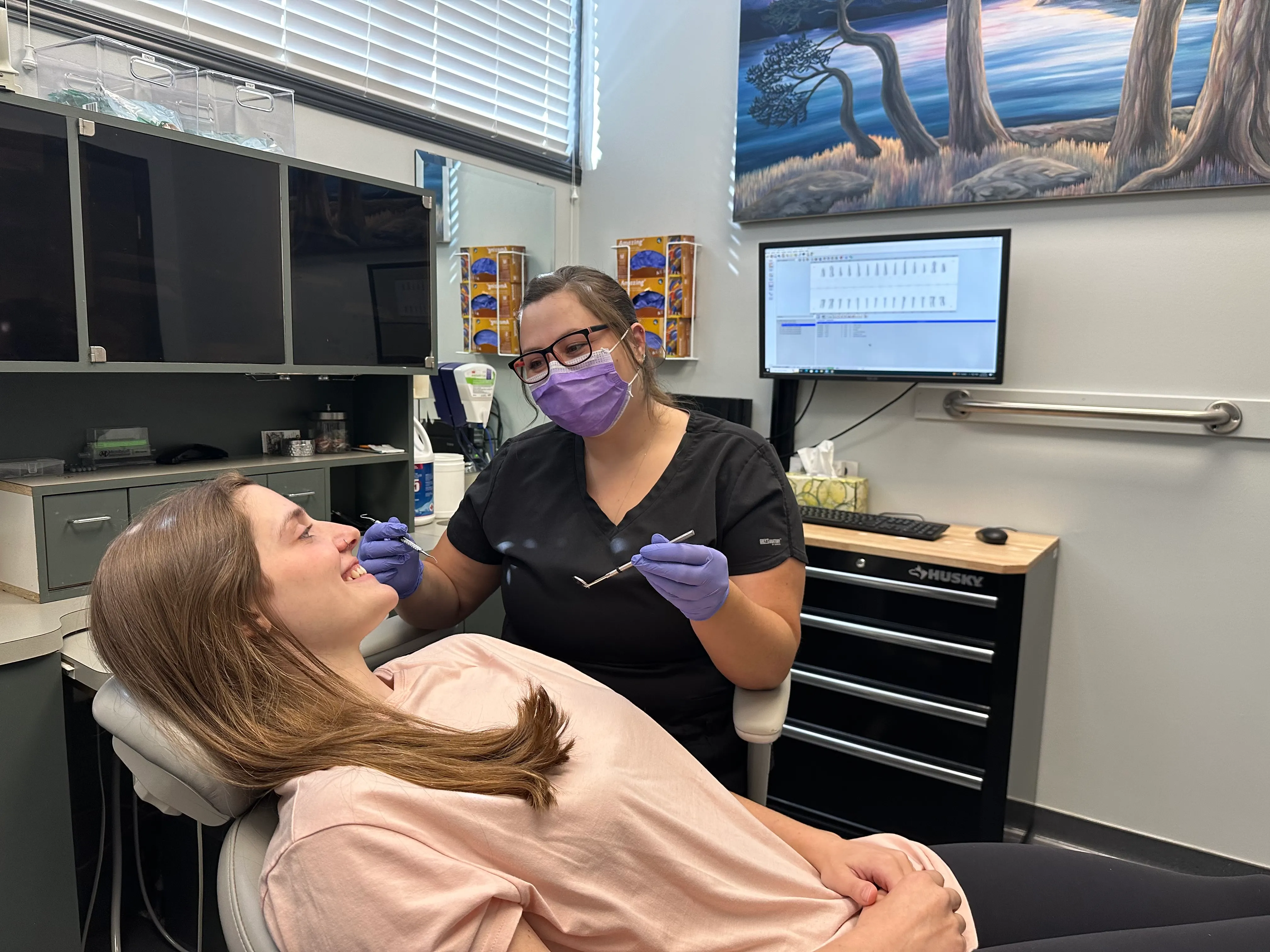 Dental assistant sits beside a patient in a dental chair at Metral Dental