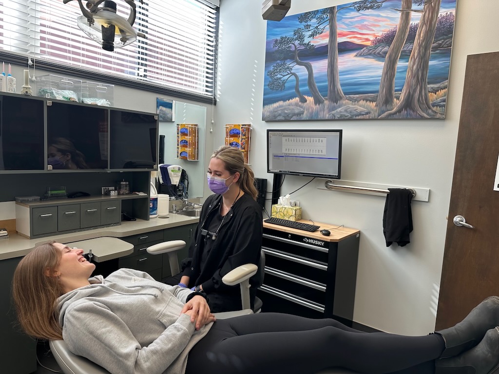 Patient in dentist chair at Metral Dental office with a dental assistant sitting beside chair