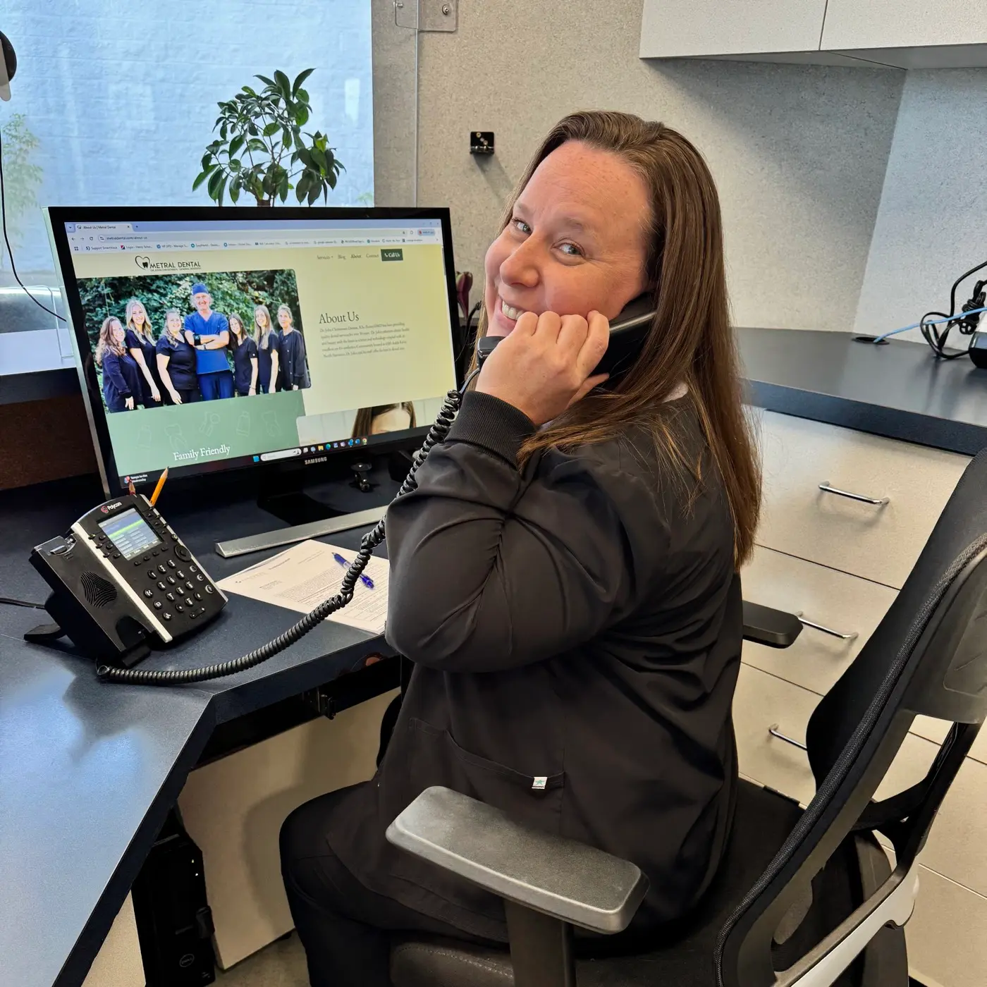Smiling Metral Dental team member answering the phone at the front desk