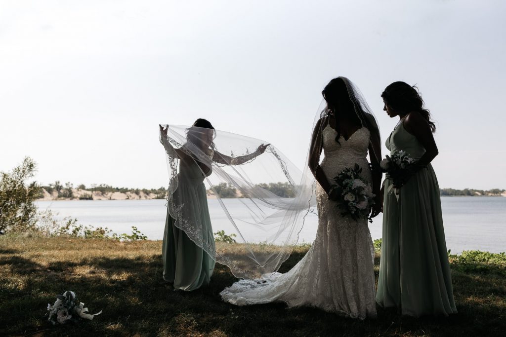 bridesmaids help bride with dress pec backyard wedding