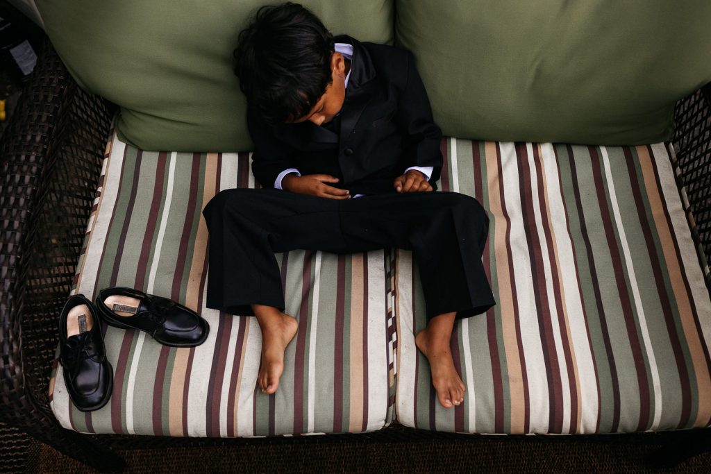 child sleeps in tuxedo at backyard wedding pec