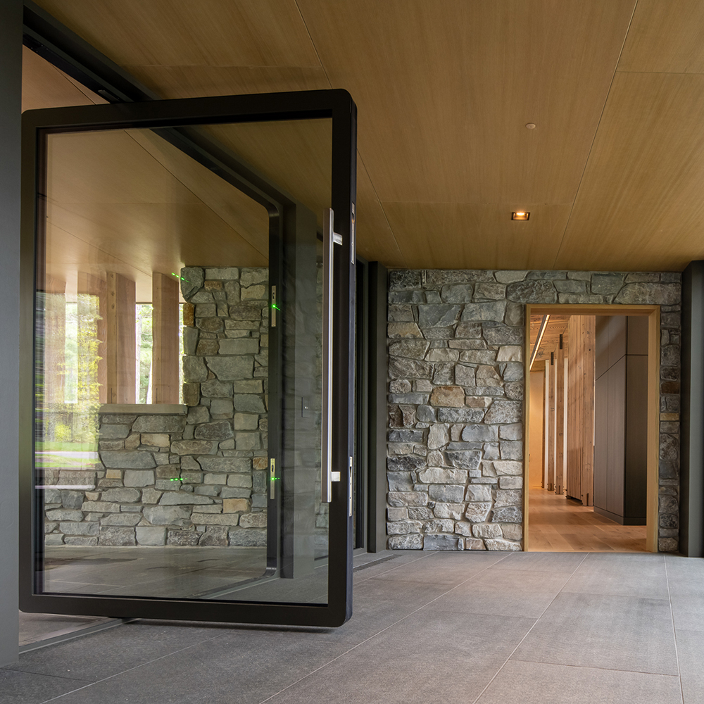 A woman opening a larger glass door from her bedroom to a terrace.
