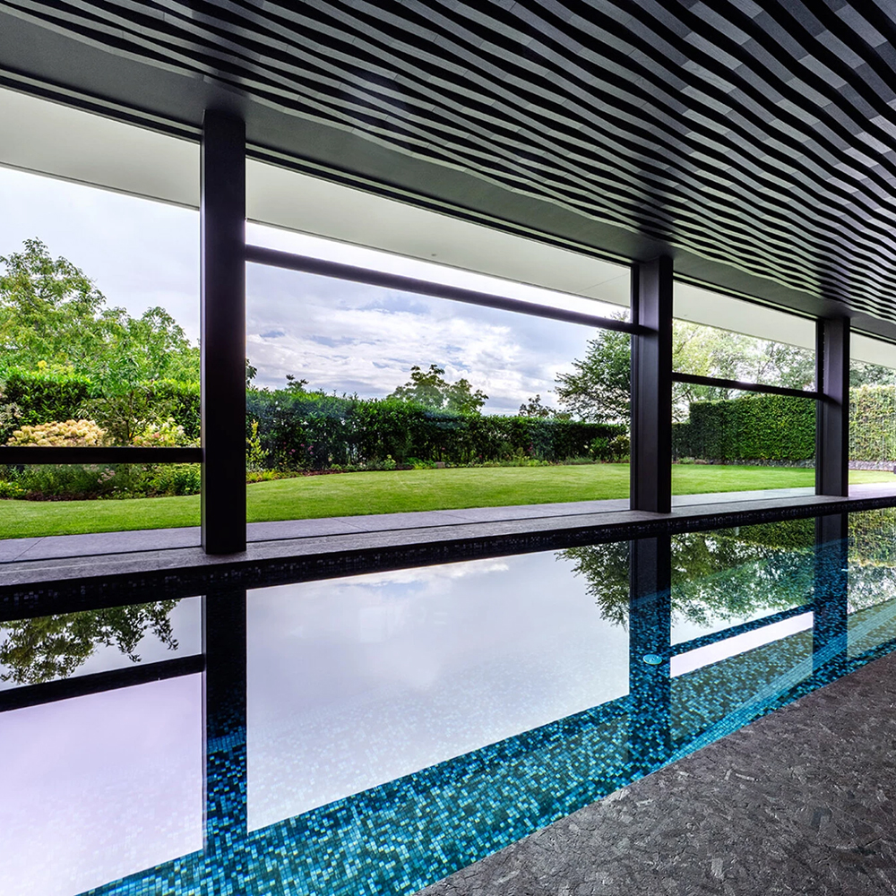 A pool house with glass walls in the mountains. 