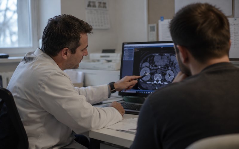 Lekarz omawia z pacjentem obraz nerek w tomografii komputerowej