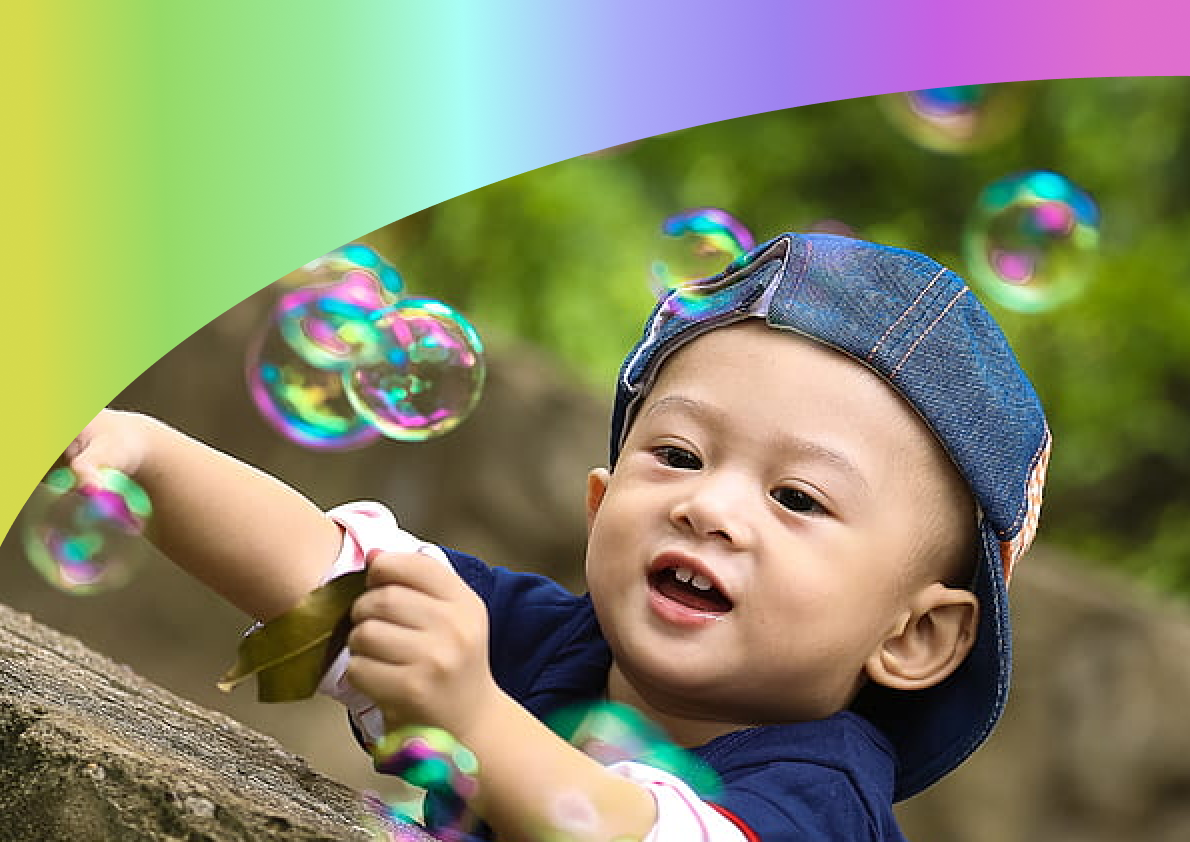 A picture of a small child playing with bubbles with a rainbow graphic at the top.