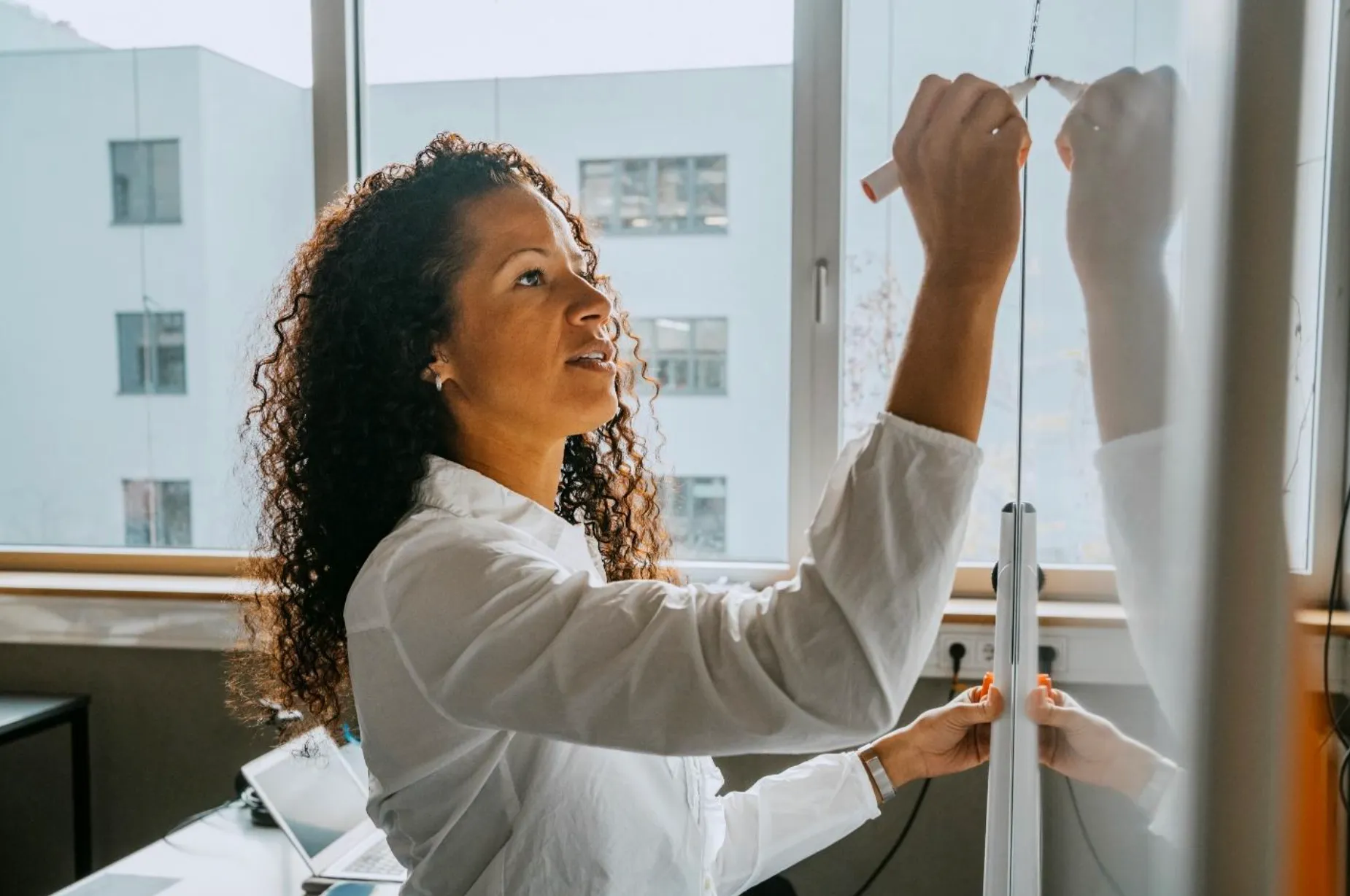 Woman writing on a whiteboard inside an office