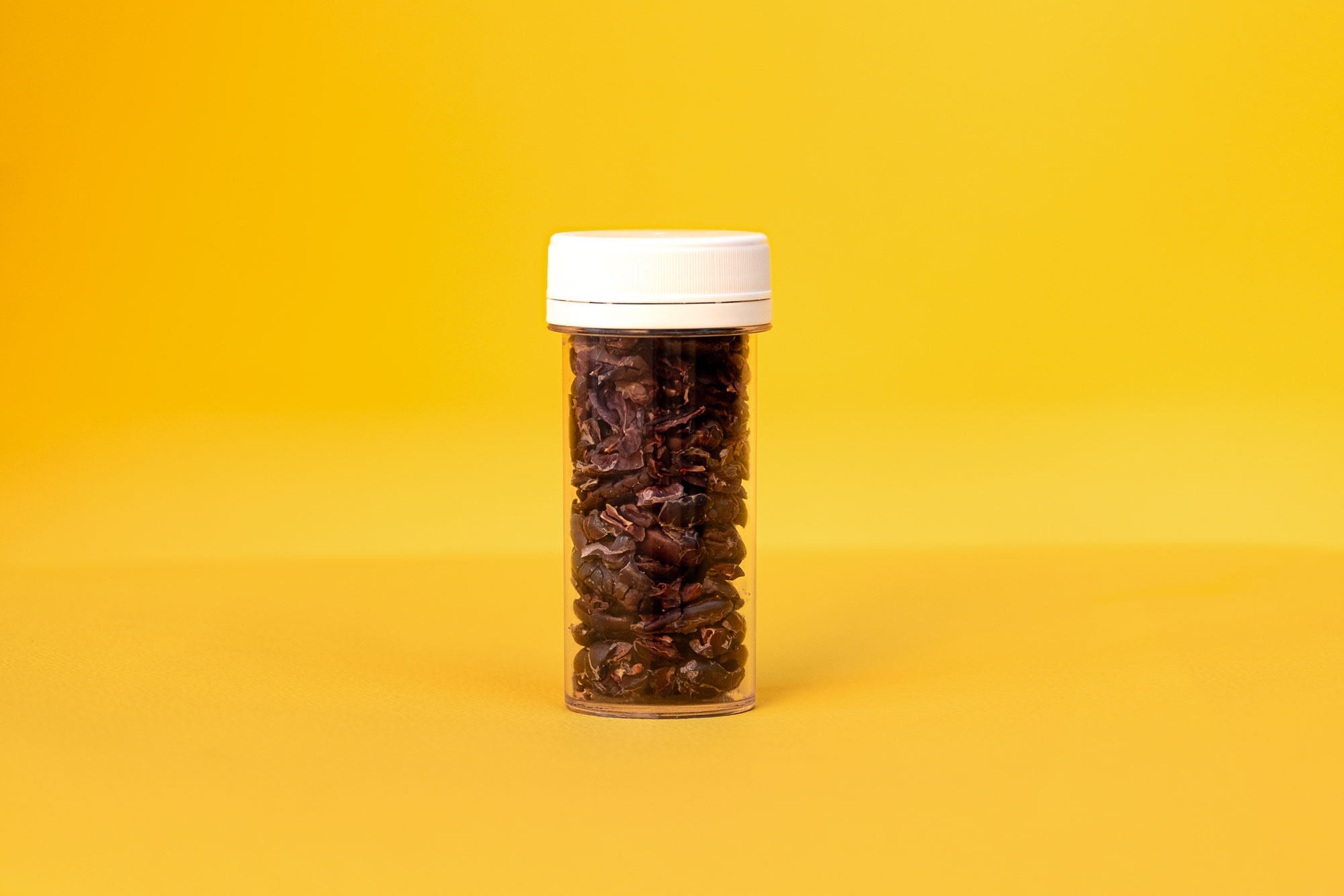 cacao nibs in a jar with yellow background