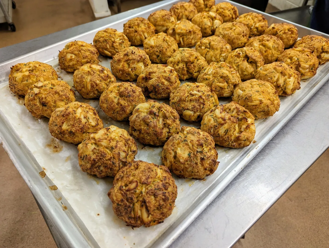 Tray of golden-brown Maryland crab cakes prepared by 700 South Deli and Catering in Linthicum Heights, Maryland