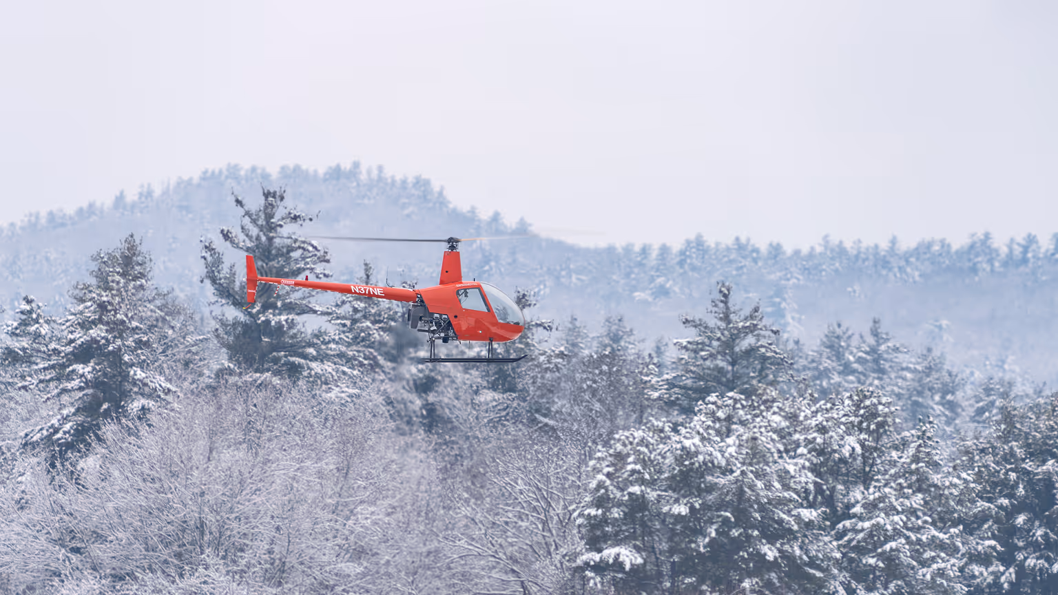 Rotor Technologies RPX helicopter N37NE flying over snow-covered pine trees during cold weather testing
