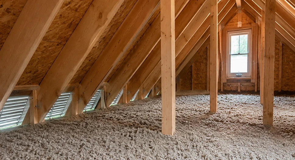 Blown-in attic insulation covering an attic floor with wooden rafters, helping reduce heat loss and prevent ice dams