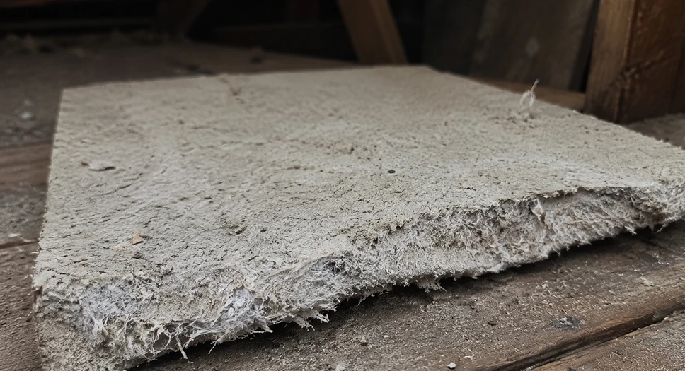 Suspected asbestos insulation board with fibrous edges in an attic.