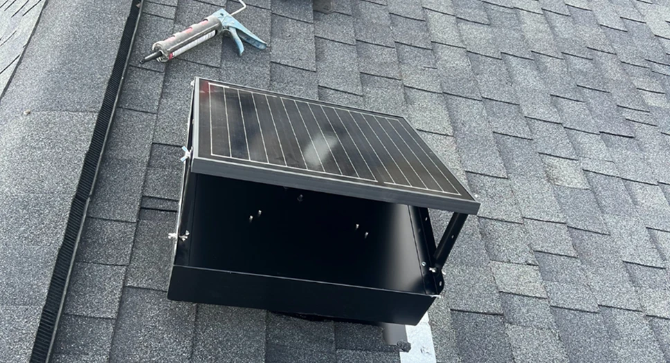 Solar attic fan installed on an asphalt shingle roof during setup on a residential home.