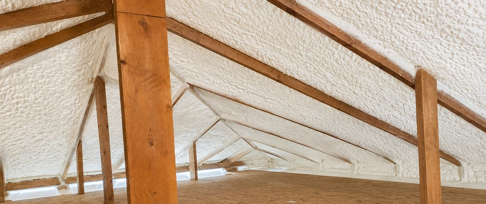 Spray foam insulation installed along attic roof rafters to improve thermal performance and air sealing.