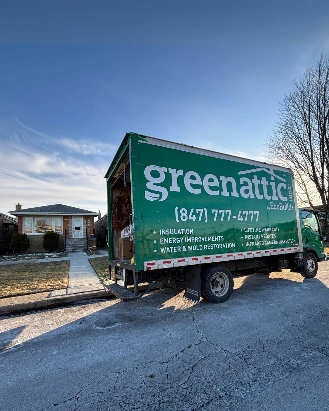 Green Attic box truck parked outside a Chicago brick bungalow with the rear door open during a service call