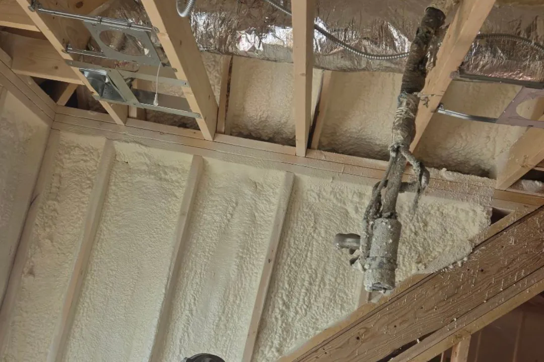Spray foam insulation around electrical conduit, junction boxes and ductwork in wall framing