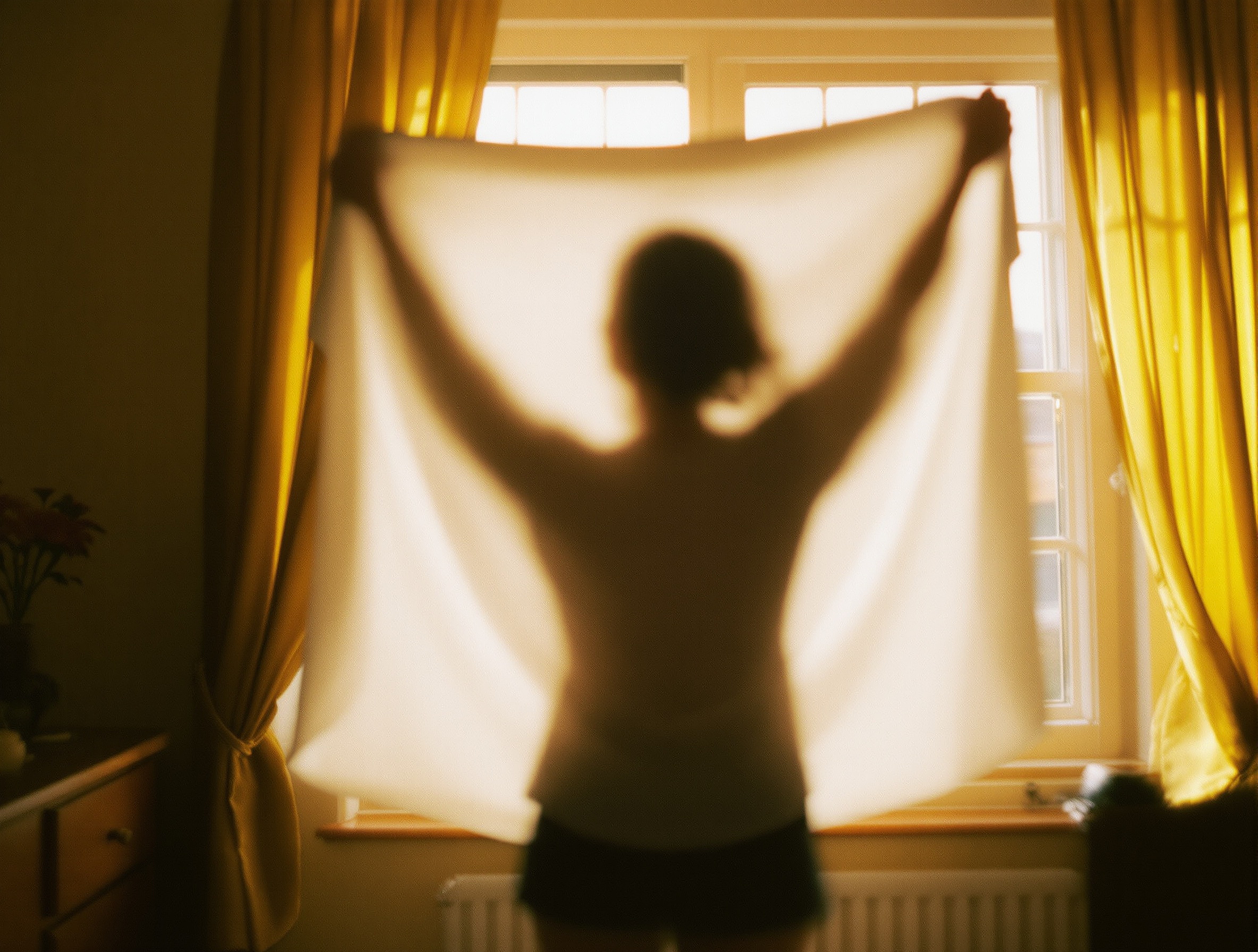 Silhouette de dos inspectant un vêtement blanc contre la lumière naturelle d