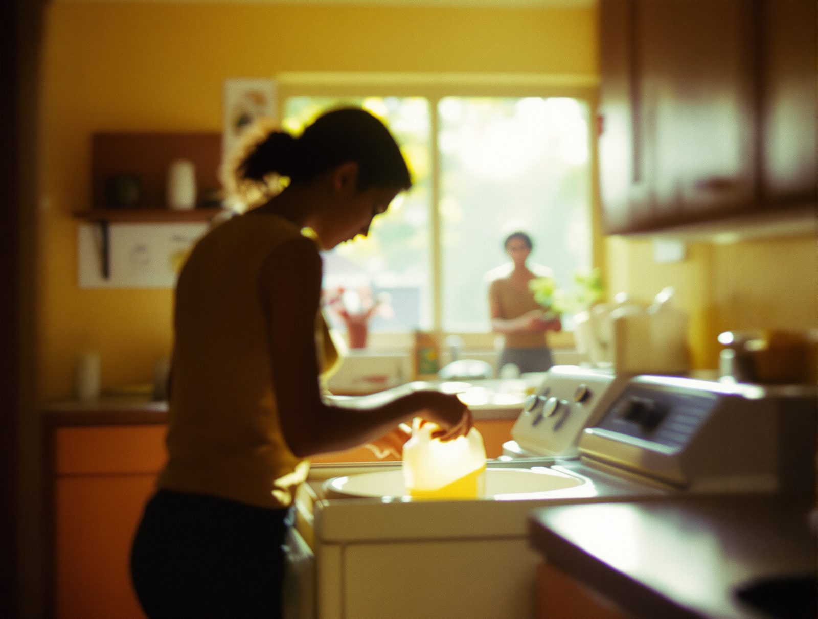 Personne de dos versant du vinaigre blanc dans le bac adoucissant de la machine a laver en lumiere naturelle