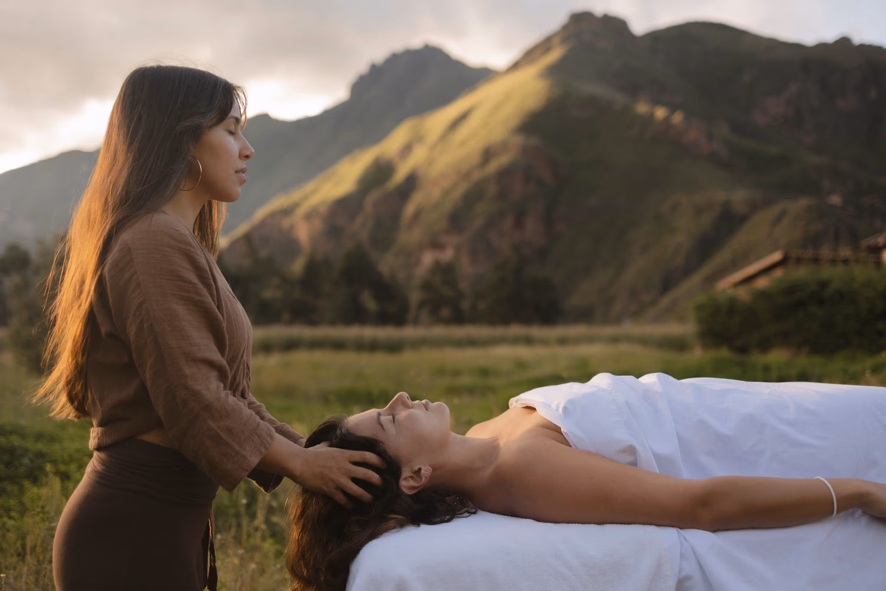A woman laying on a bed with a mountain in the background.