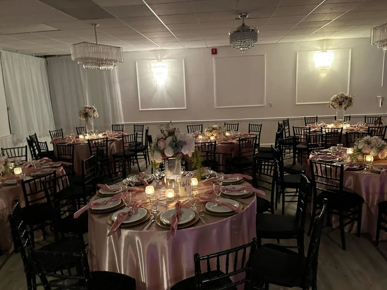 Charming setup at The Palmyra Venue in New Jersey, featuring round tables adorned in pink and gold with beautiful flower centerpieces in various shades of pink