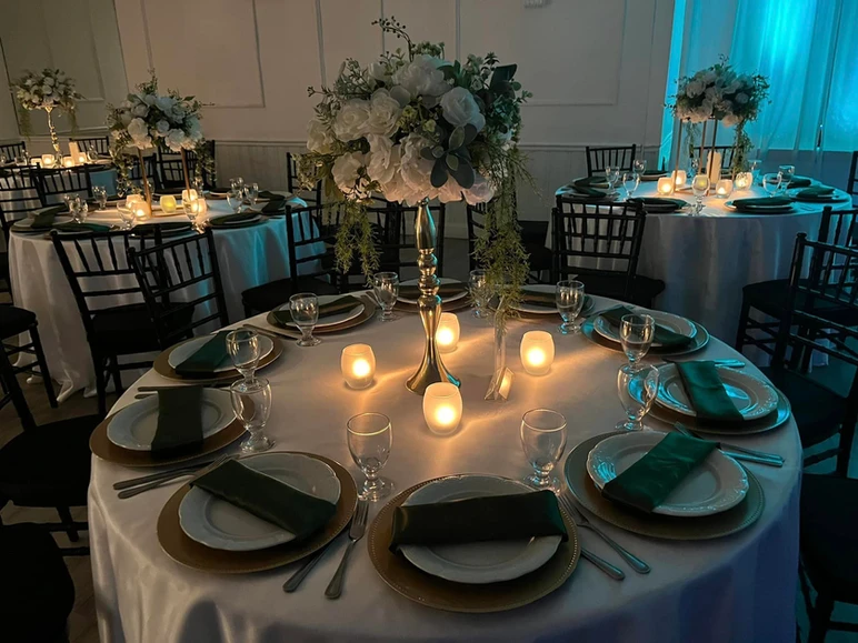 Exquisite table decor at The Palmyra Venue in New Jersey, featuring a stunning green and gold color scheme with beautiful white and green flower centerpieces
