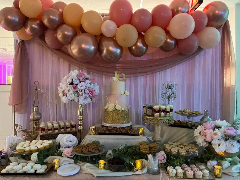 Sweets table featuring a centerpiece cake adorned with exquisite pink and gold-themed decorations at  The Palmyra Venue in New Jersey.