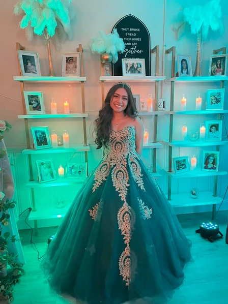 A joyful girl, dressed in a beautiful blue princess dress, radiates happiness amidst a backdrop of enchanting pictures and candles at The Palmyra Venue in New Jersey