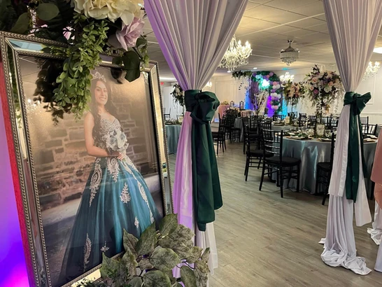  Close-up of a framed picture capturing a smiling girl in a beautiful blue dress, in the background, round tables of a special moment at The Palmyra Venue in New Jersey.