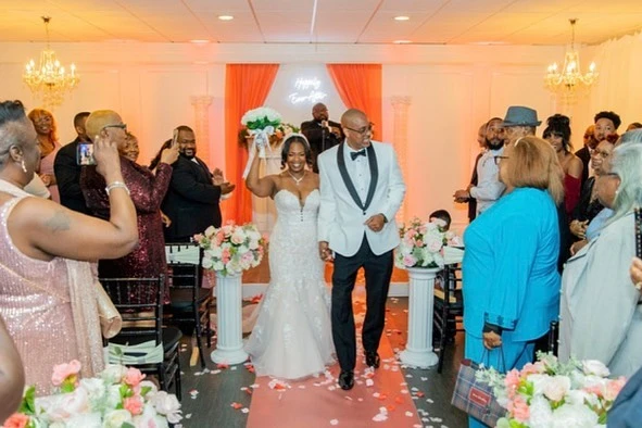 Radiant bride wearing a joyful smile, walking down the aisle with her groom as guests joyfully stand and cheer.