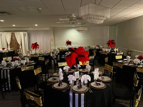 Round black tables adorned with red, gold, and black themed decorations, featuring striking red and black centerpieces at The Palmyra Venue, New Jersey.