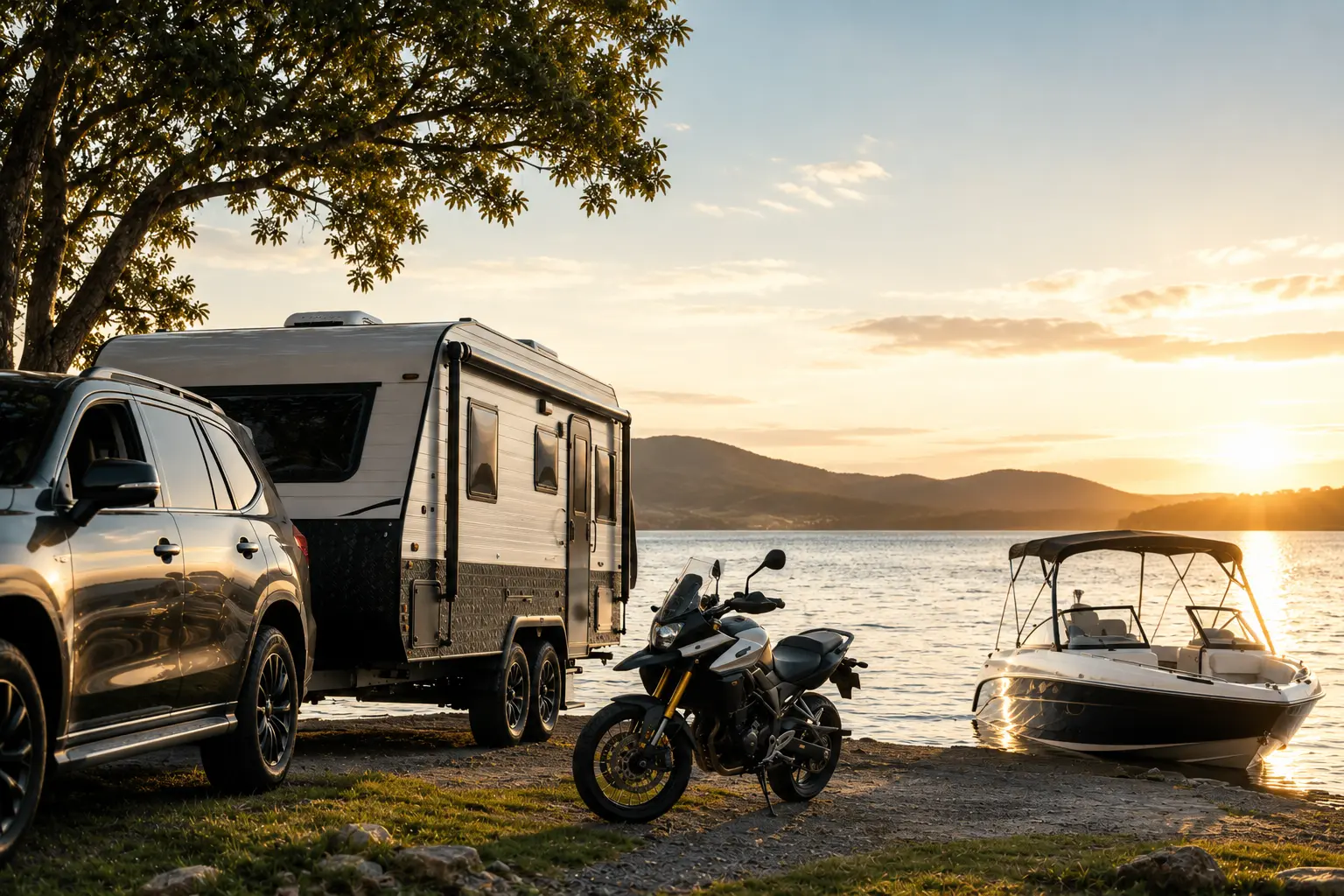 SUV with camper trailer and motorcycle parked by lake shore near a boat at sunset.