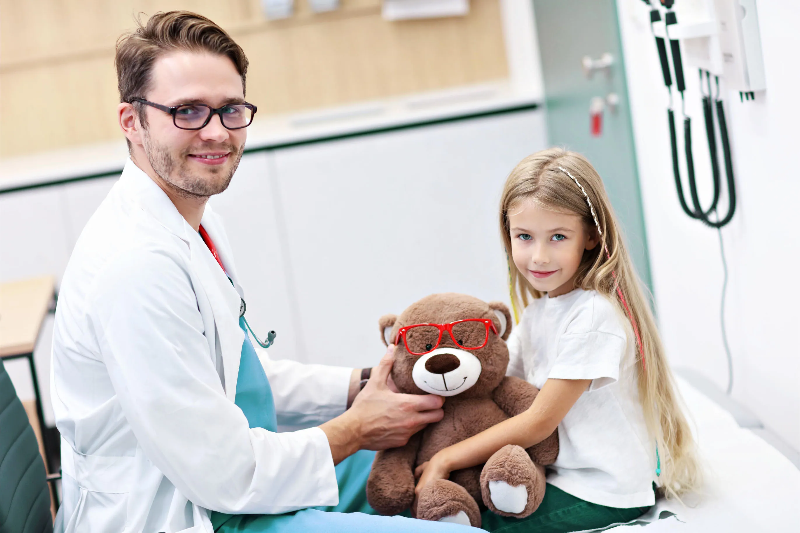 педиатър си играе с дете, дал му е меченце играчка